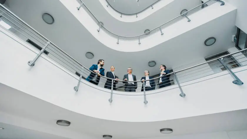 Partner von Stecker Berger + Partner stehen am Geländer im 1. Stock des Firmengebäudes in Kassel