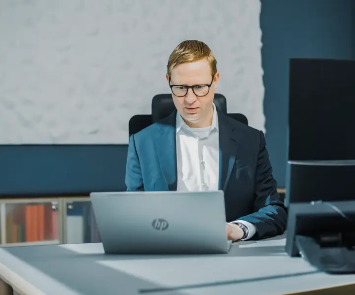 Ein Mann sitzt am Schreibtisch an einem Laptop